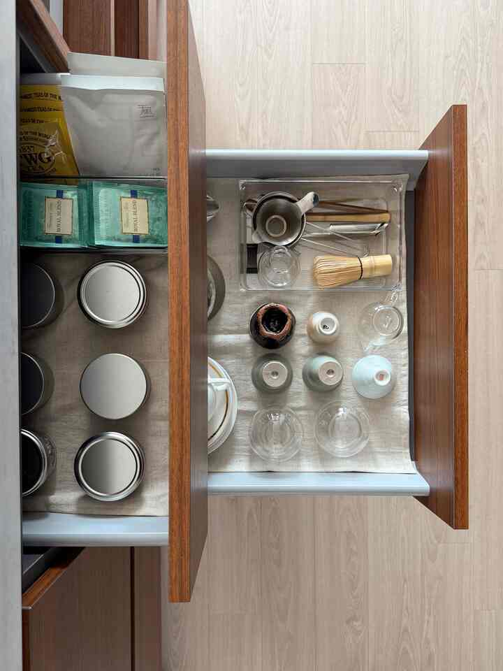 ベージュ色調のキッチン収納スペース、整然と配置された茶器具とキッチン用品の引き出し内部