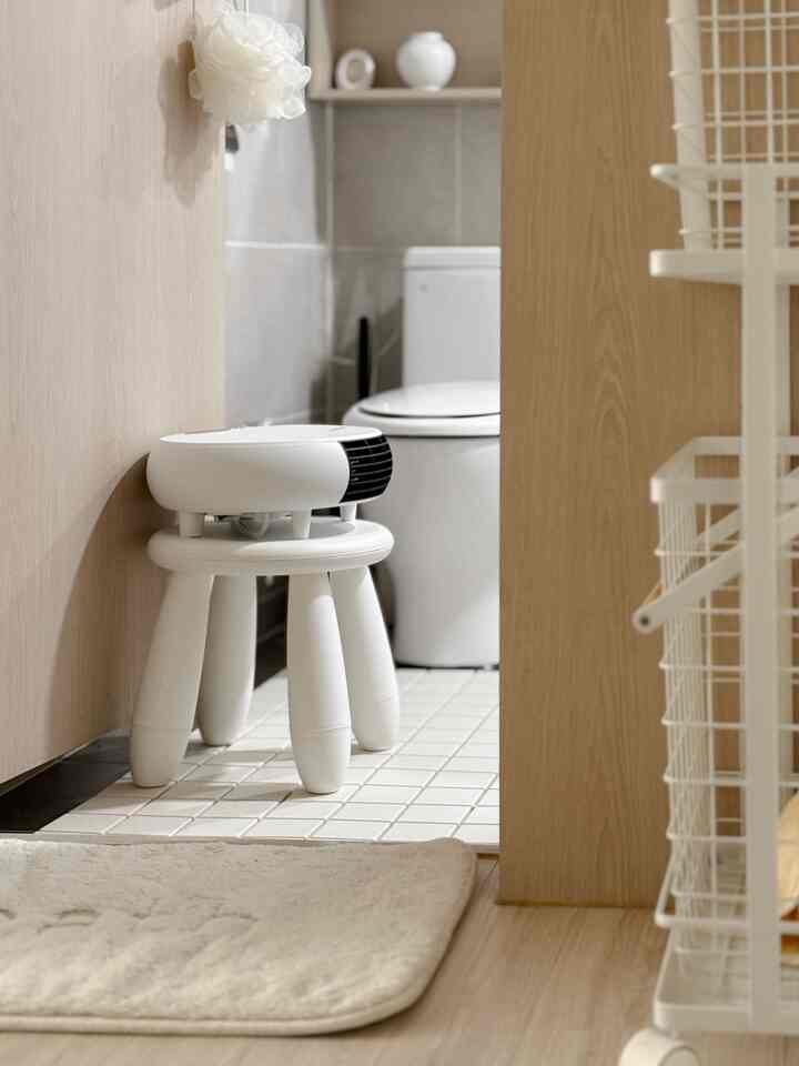 白とライトウッド調のバスルーム空間、スツールとバスマットが配置された清潔感のあるモダンなインテリア