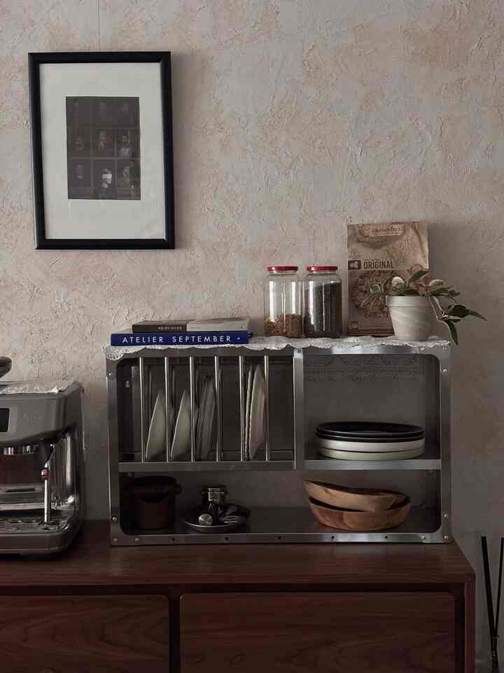 ブラウンとグレーの色調のキッチン、ステンレス製キッチンラックと食器、木製収納キャビネットが配置された雰囲気のあるインテリア