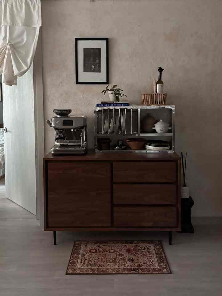 温かみのあるブラウンとベージュの色調のキッチン、木製のサイドボードの上にステンレス製のキッチンラックとコーヒーマシンが配置されたナチュラルなインテリア