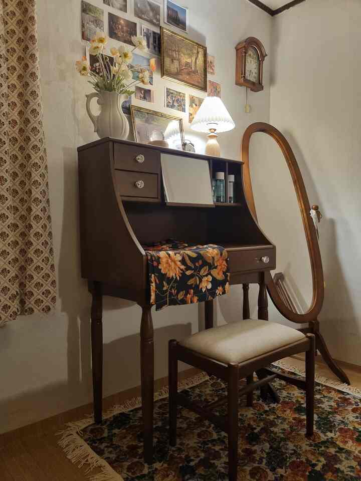 茶色とベージュのトーンのクラシックなレトロハウスのパウダールーム、アンティークの化粧台とスツール、大きな楕円形の鏡が配置された落ち着いた空間