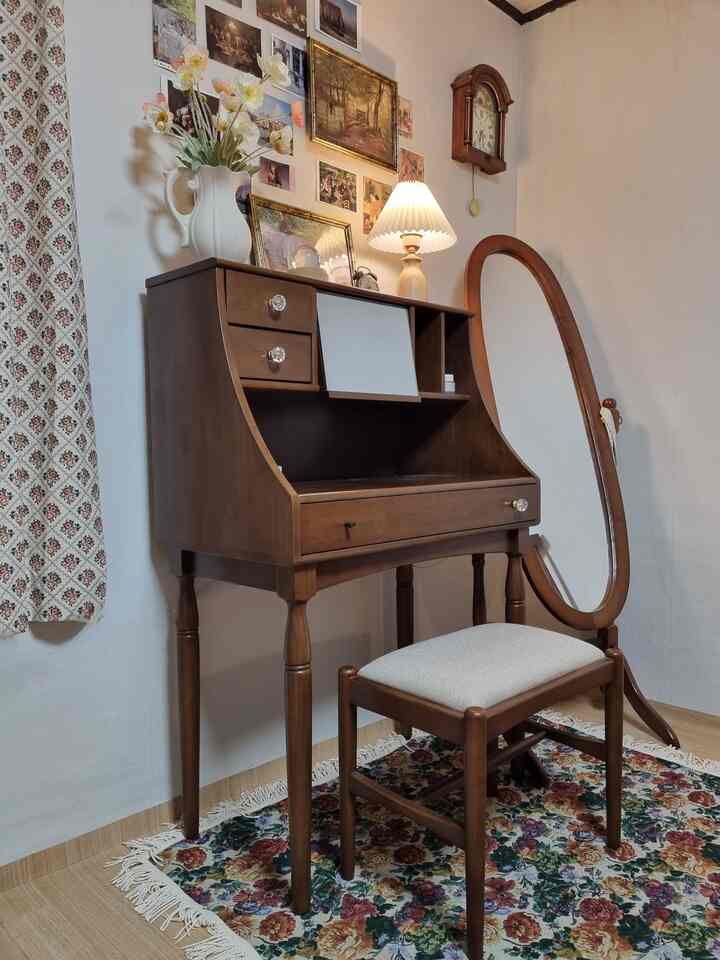 木目調のクラシックヴィンテージ化粧台とスツール、楕円形の全身鏡とテーブルランプが配置された雰囲気のある空間