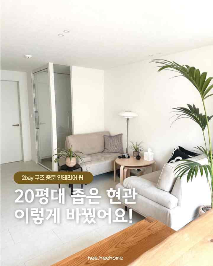 白を基調とした狭い玄関空間、スリムフレーム中門とベージュのソファ、丸いスツールが配置されたモダンでナチュラルなインテリア