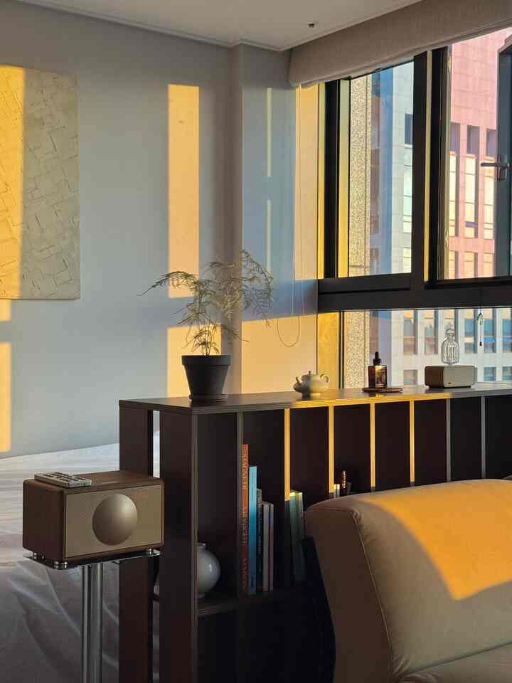 温かみのある木目調のレトロスタイルのワンルームリビング、中央に配置された低めのウォールナット本棚が印象的な雰囲気のある空間