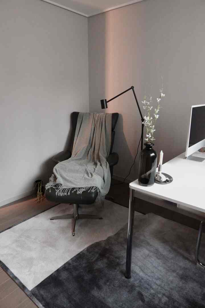 グレーと黒のナチュラルカラーのホームオフィス、リクライニングチェアと机、モダンな照明が配置されたシンプルモダンなインテリア