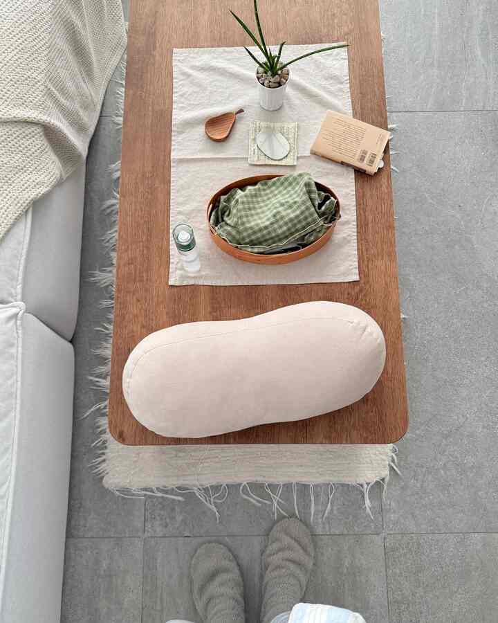 ナチュラルな色調のリビング、木製テーブルと白いソファ、柔らかなクッションが配置された居心地の良いインテリア