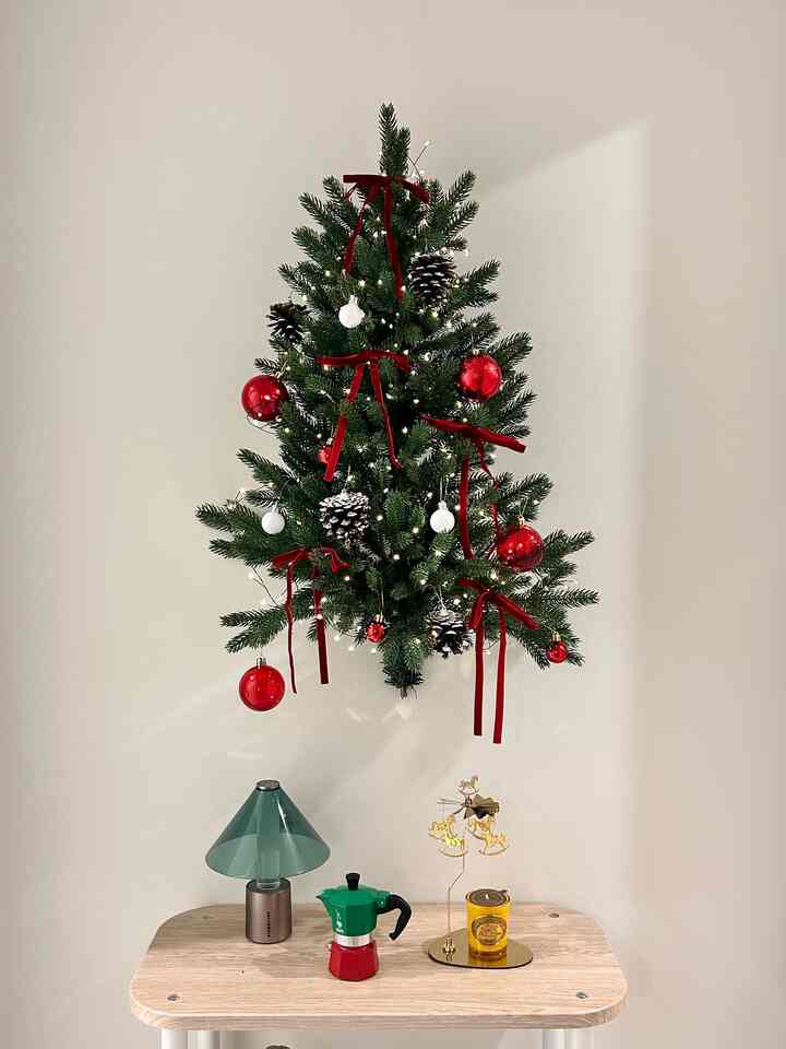 Red and green hanging Christmas tree with simple mini table featuring home cafe items in an entrance space