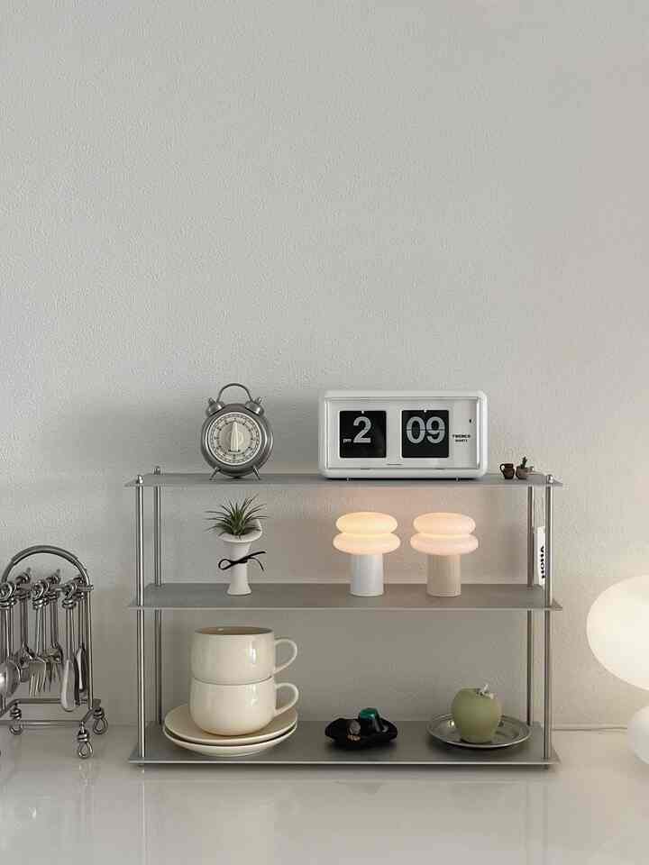 白い背景にミニマルな金属の棚と照明が配置されたコンパクトなキッチンコーナー