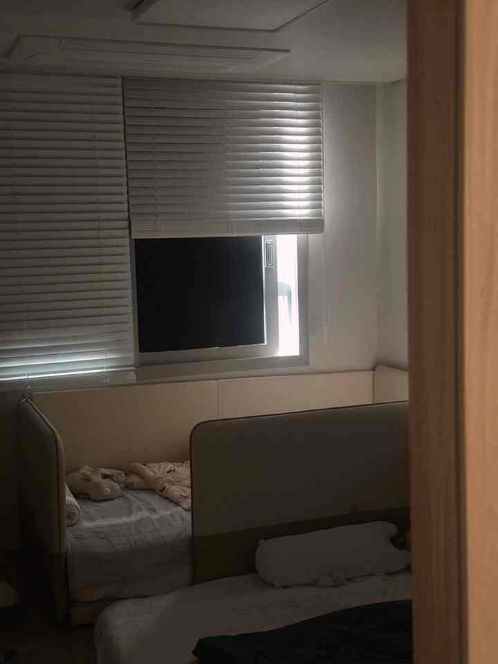 白を基調とした子供部屋、ベビーベッドとロータイプベッドが配置された落ち着いたナチュラルな雰囲気の空間