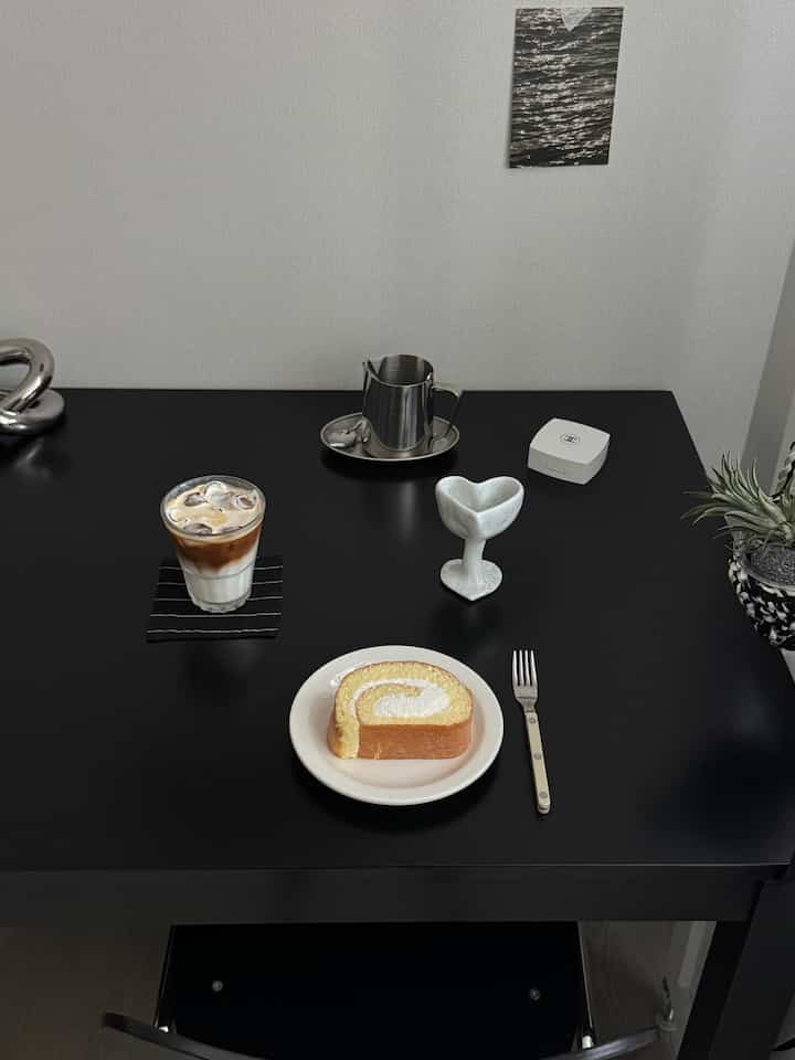 黒を基調としたクラシックなダイニングテーブルにホームカフェのデザートとカトラリーが配置されたミニマルなインテリア
