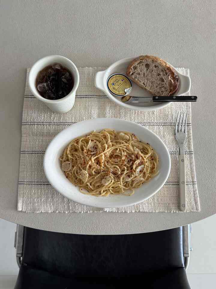 明るいベージュ色のテーブルに白い皿とカップが配置されたミニマルなおうちカフェの空間