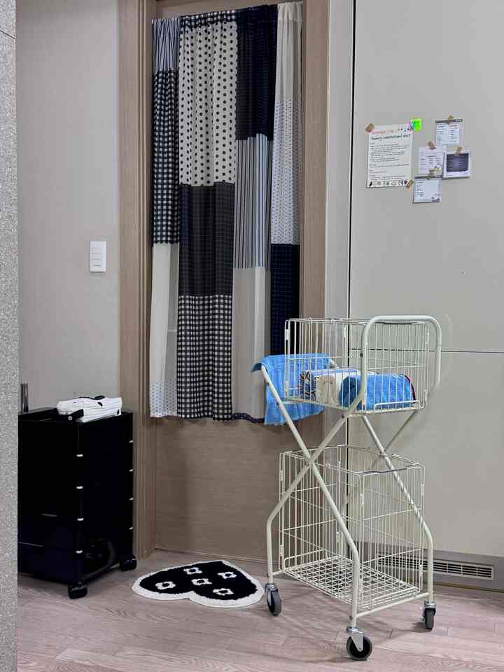 ホワイトとウッドトーンの調和したトイレ、移動式洗濯かごと収納キャビネットが配置された整理されたインテリア