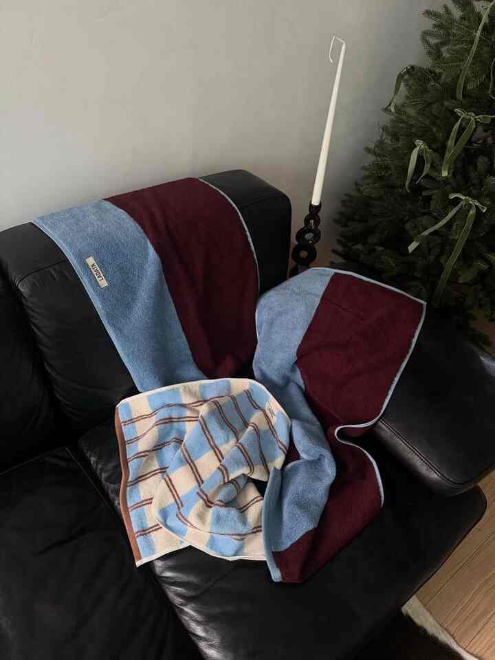 ブルーとブラウンの色調が特徴のリビング、黒のレザーソファにタオルが置かれた雰囲気のあるインテリア