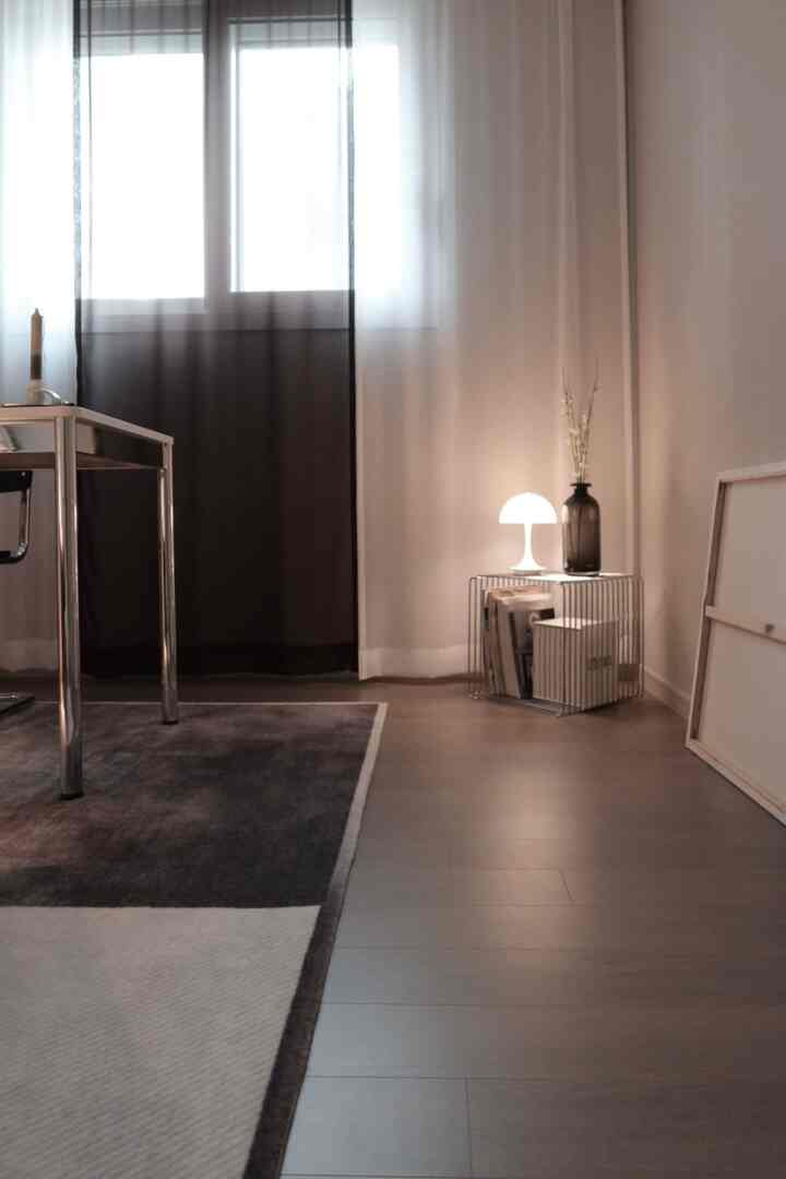 ナチュラルカラーのモダンなホームオフィス空間、メタルデスクと小さなテーブルランプが配置されたシンプルなインテリア