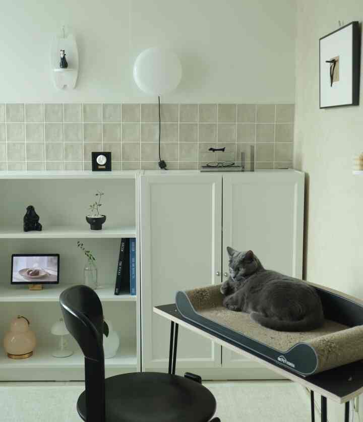 White and beige toned living room featuring a cat scratching post and wall shelf in a natural modern style space