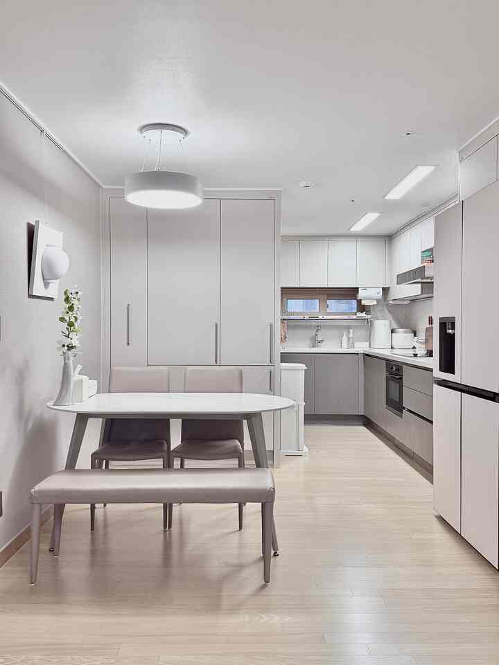 ナチュラルモダンな雰囲気のアパートキッチン、白いダイニングテーブルとグレーのダイニングチェアが整然と配置された空間