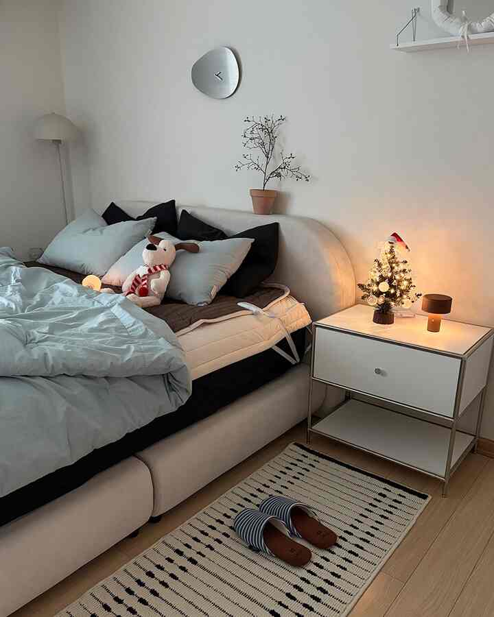 グレーの寝具と白いナイトテーブルが配置されたシンプルでナチュラルな寝室のインテリア