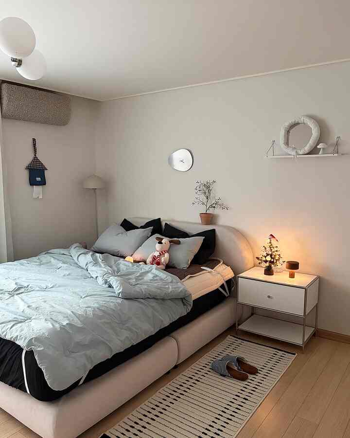 明るいアイボリー色の家具と白い壁に青い寝具が配置された清潔感のある寝室のインテリア