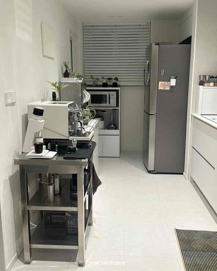 白とシルバーの色調の狭い一列型キッチン、コーヒーマシンと棚が配置されたモダンで効率的なインテリア