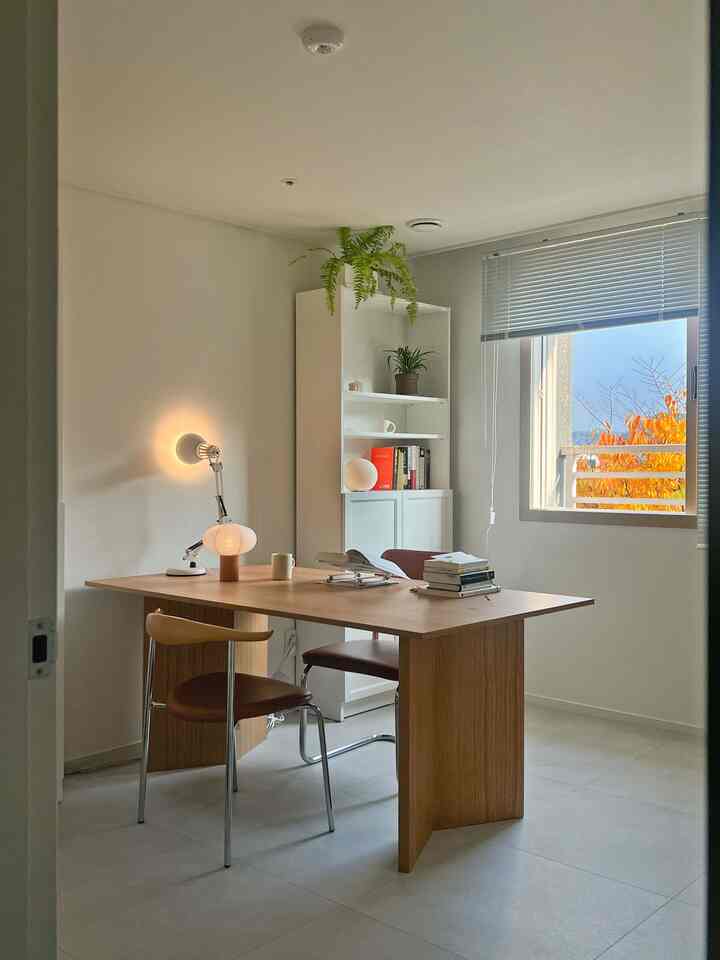 ホワイトと木目調の調和が美しい書斎兼ホームオフィス、大きな木製デスクとイケアの本棚が配置された雰囲気のある作業空間