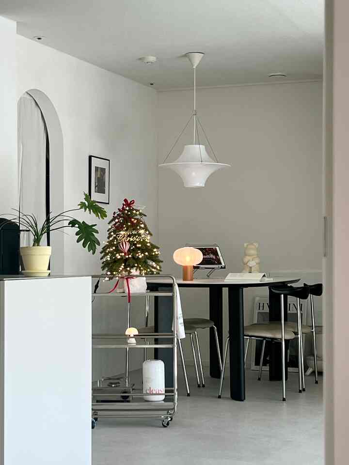 白い壁と天井を背景にしたキッチンダイニング、黒のセラミックダイニングテーブルと椅子が配置されたモダンでミニマルな雰囲気のインテリア