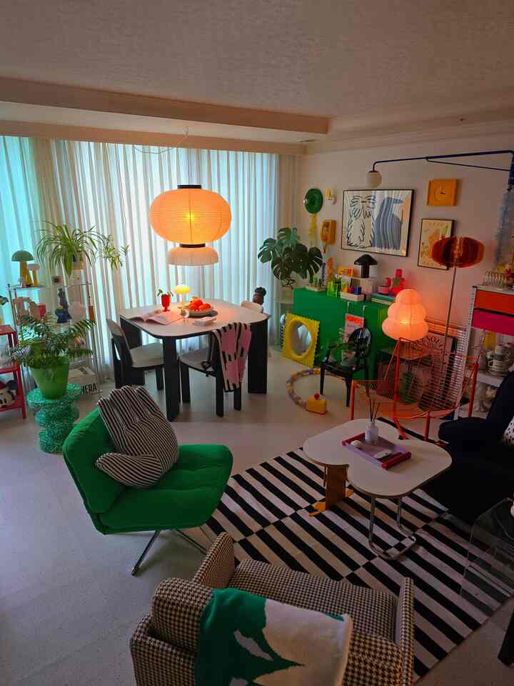 Living and dining room with white curtains backdrop, featuring colorful furniture and lighting in an Art Deco style