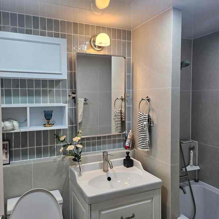 グレーとホワイトの色調のバスルーム、ヴィンテージの小物や洗面台、タオル掛けが配置された印象的でモダンな空間