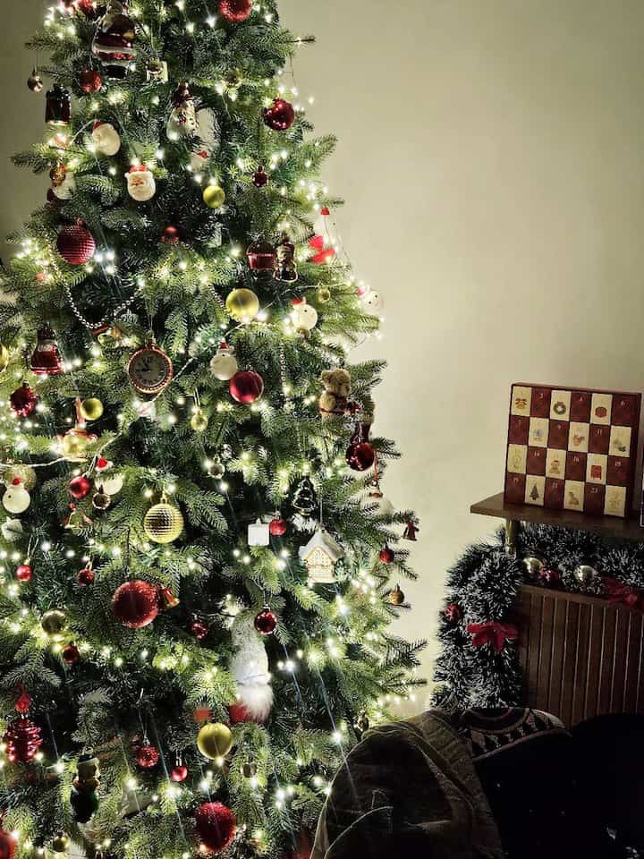 白いライトと赤い飾りが施された大きなクリスマスツリーがあるワンルームの雰囲気あるインテリア
