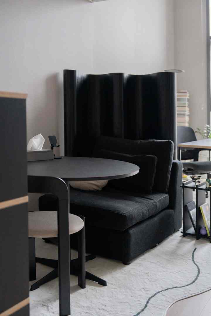 モダンでシンプルな雰囲気のリビングルーム、黒いソファと丸いダイニングテーブル、黒の間仕切りパーティションが配置されたインテリア