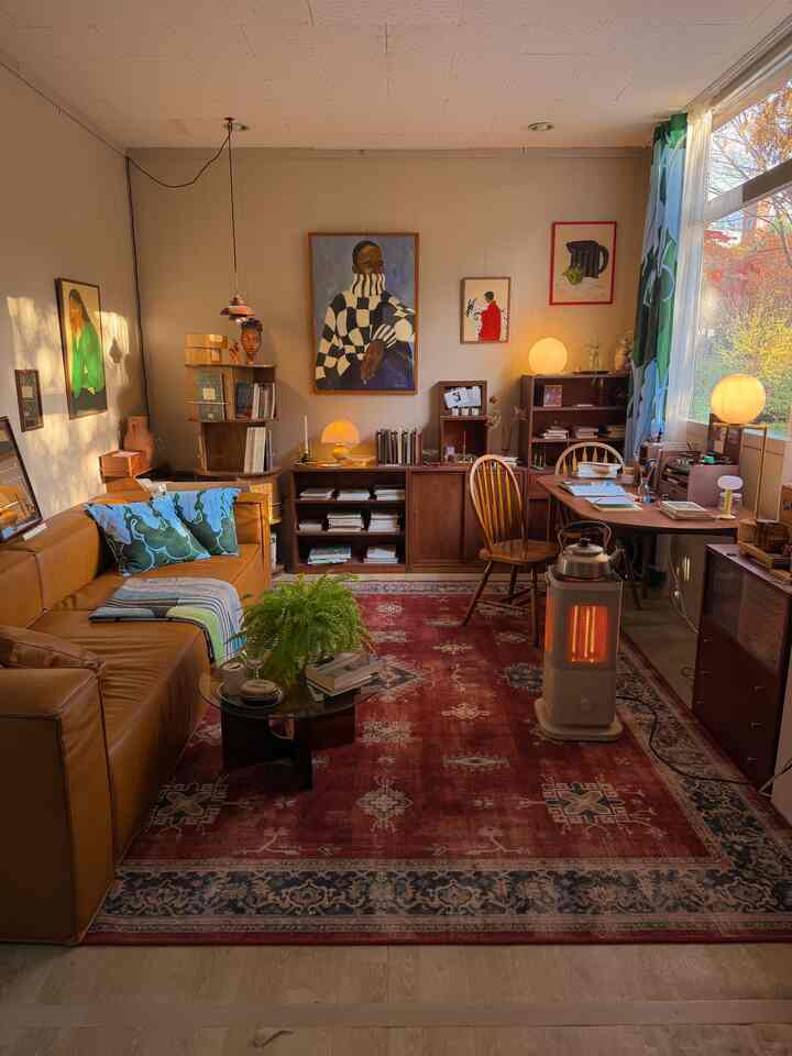 Warm brown toned living room featuring wood furniture, leather sofa, and a red patterned rug with cozy atmosphere