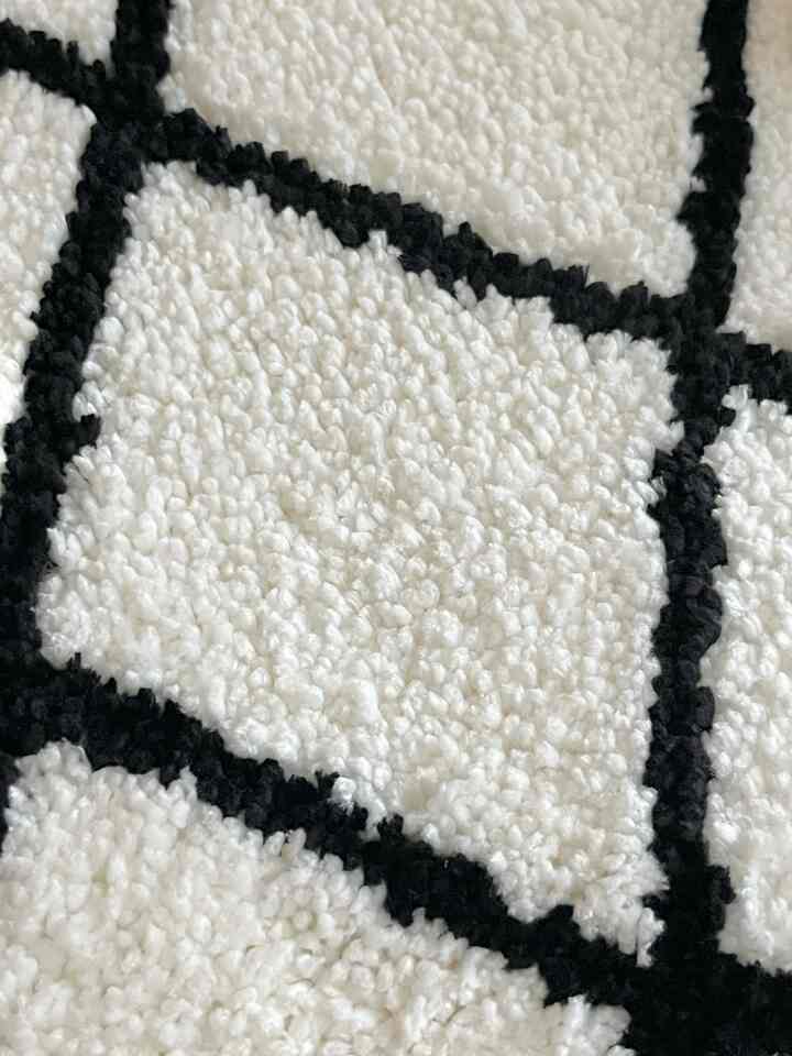 白と黒の格子模様のバスマット、柔らかな風合いが特徴的なミニマルなバスルームアクセサリー