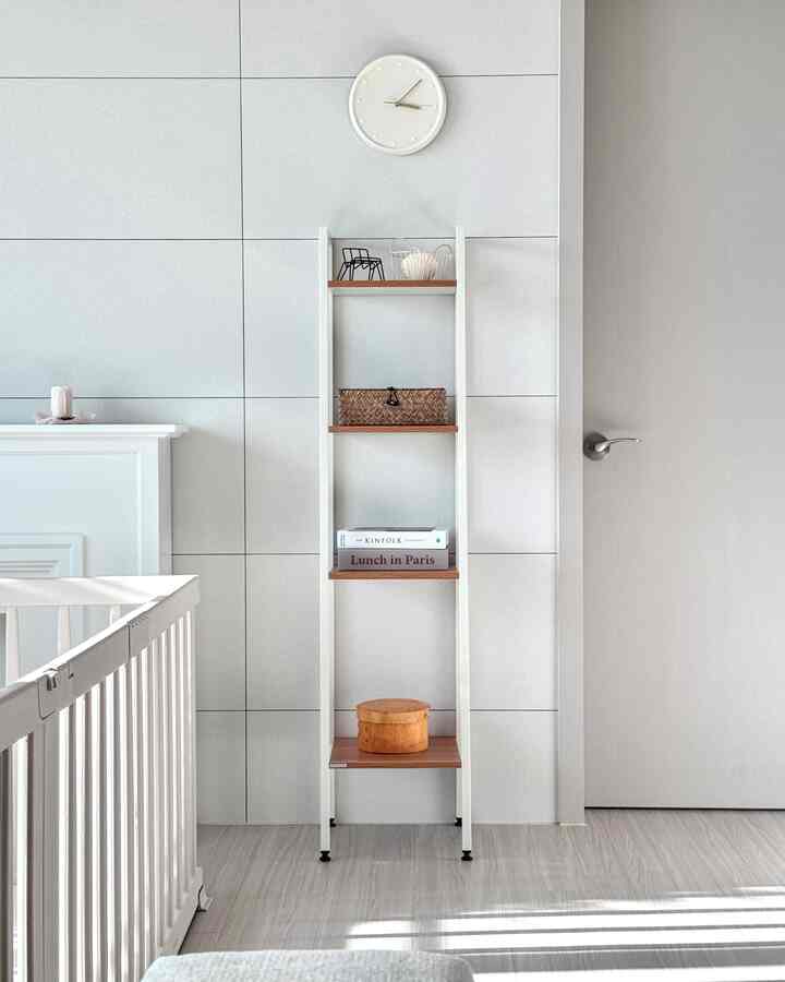 白と木目調の明るいリビング、狭い空間に本と小物を置いたシンプルな棚のある自然なモダンなインテリア