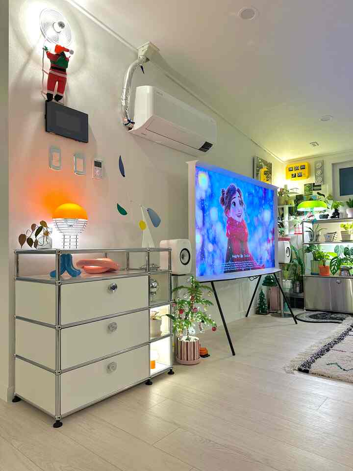 白とベージュのモダンなリビング、テレビ台とサイドボード、植物や照明が配置された雰囲気のある空間