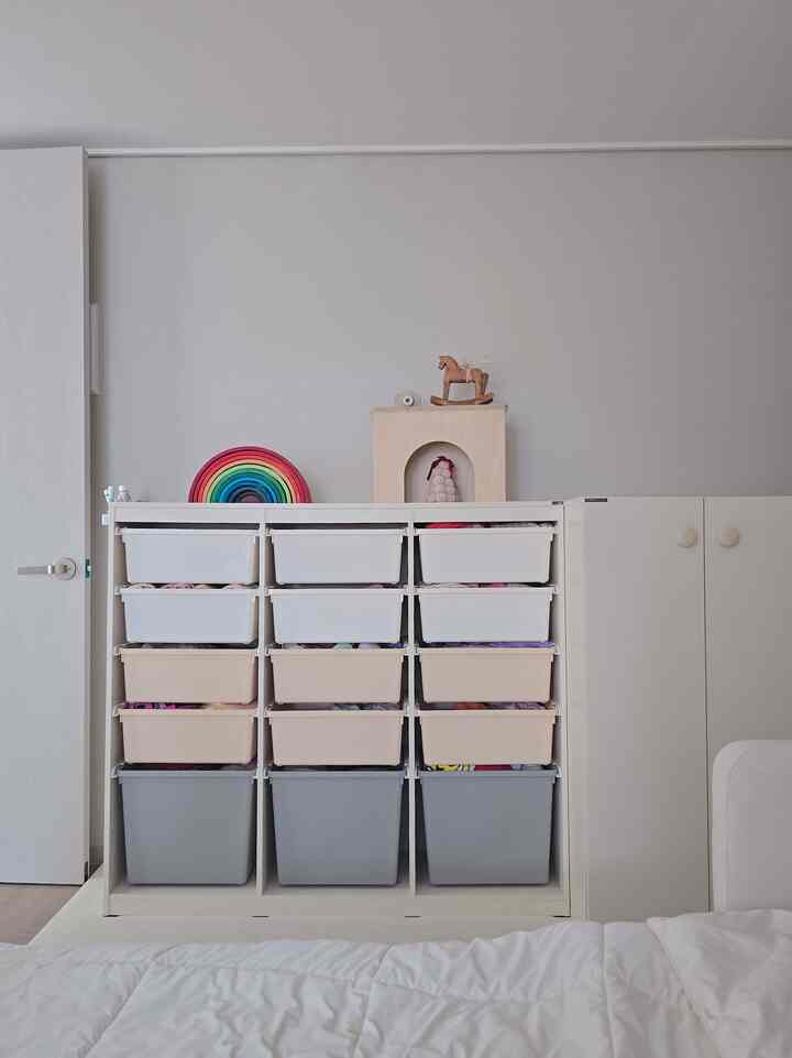 白を基調とした子供部屋のクローゼットと多数の収納ボックス、可愛らしい小物が置かれた整頓された収納スペース
