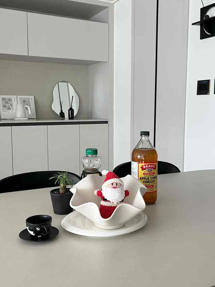 白と黒のトーンが基調のミニマルなキッチンとダイニング、テーブルの上にサンタのオブジェが配置された印象的な空間