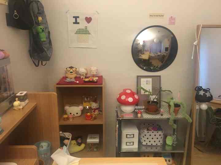 明るい白い壁とナチュラルな木製棚、かわいいおもちゃと人形が置かれた一人暮らしの清潔で居心地の良い空間