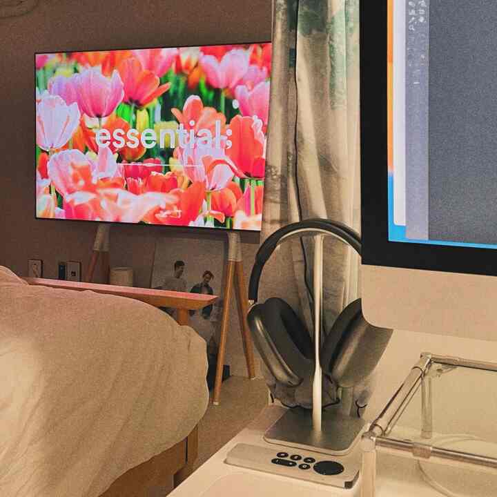 ホワイトとベージュのトーンが特徴的な寝室、ホームオフィス用iMacとテレビ台が配置された雰囲気のあるインテリア