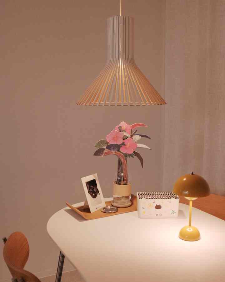 白いテーブルと木製のペンダントライトが配置されたナチュラルな雰囲気のダイニングスペース