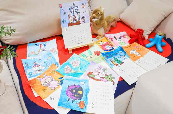 赤いブランケットとベージュのソファがあるリビング、子供のイラストカレンダーと赤いリスのぬいぐるみが配置された雰囲気のある空間