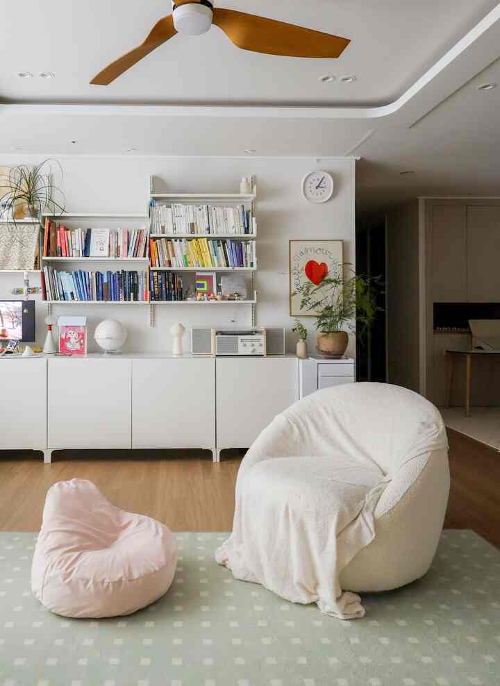 白と木目調が調和したリビング、白いビーズクッションとピンクのペットクッションが配置されたシンプルで落ち着いた空間