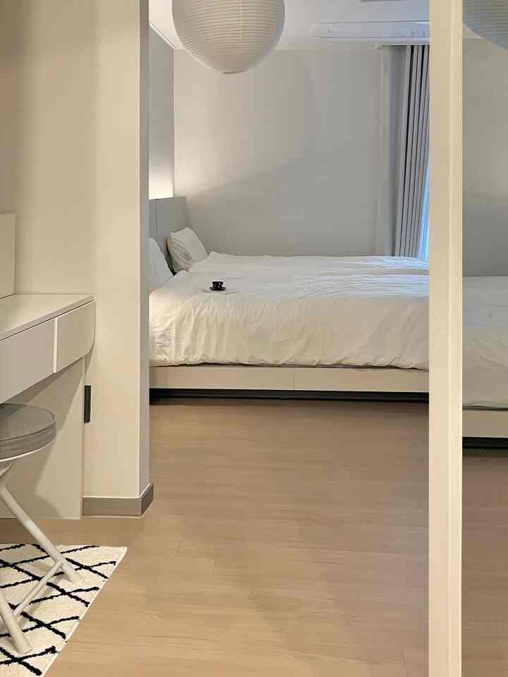 白とナチュラルカラーの寝室、和紙照明と遮光カーテンが配置された雰囲気のある空間