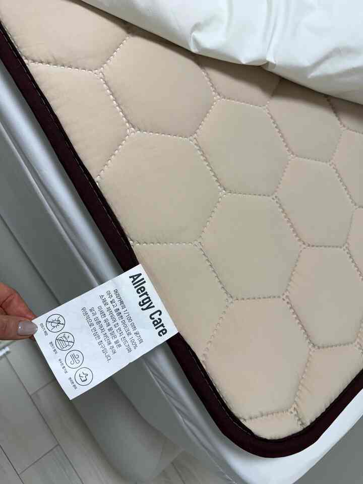 アイボリーとベージュの色調の寝室用マットレスカバー、アレルギーケアラベルが付いた清潔な寝具