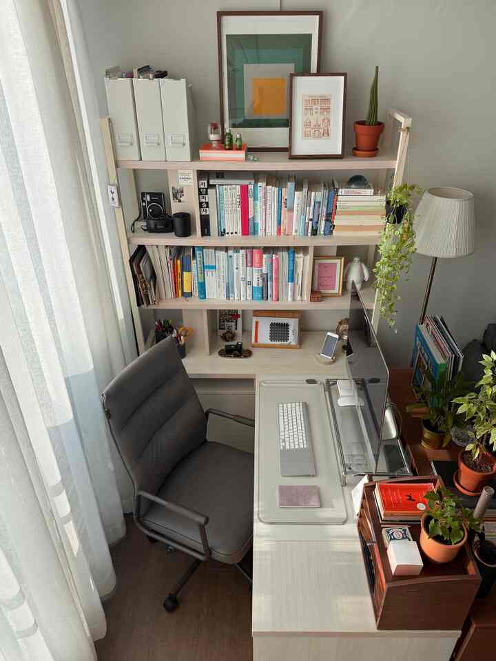 温かみのある木目調デスクとグレーオフィスチェアが調和した、明るい光の差し込むすっきりとしたホームオフィス