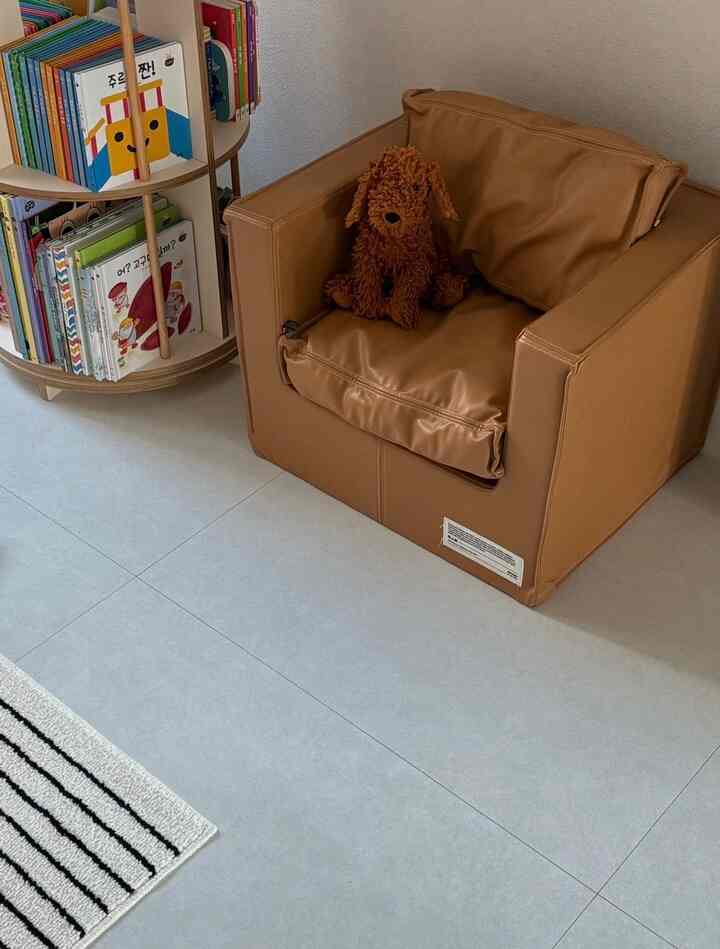 ブラウンのウッドトーンの子供部屋、レザーのベビーソファと円形の本棚が配置された雰囲気のあるインテリア