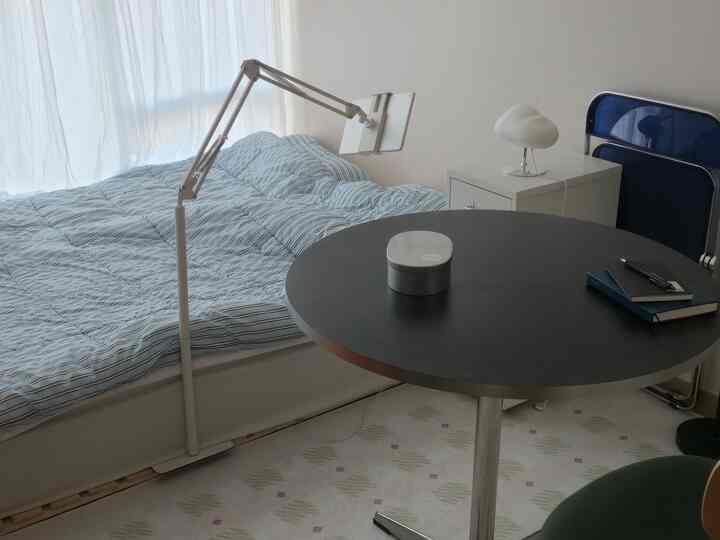 White and blue toned small bedroom featuring a bed and round dining table with a simple, minimalist atmosphere