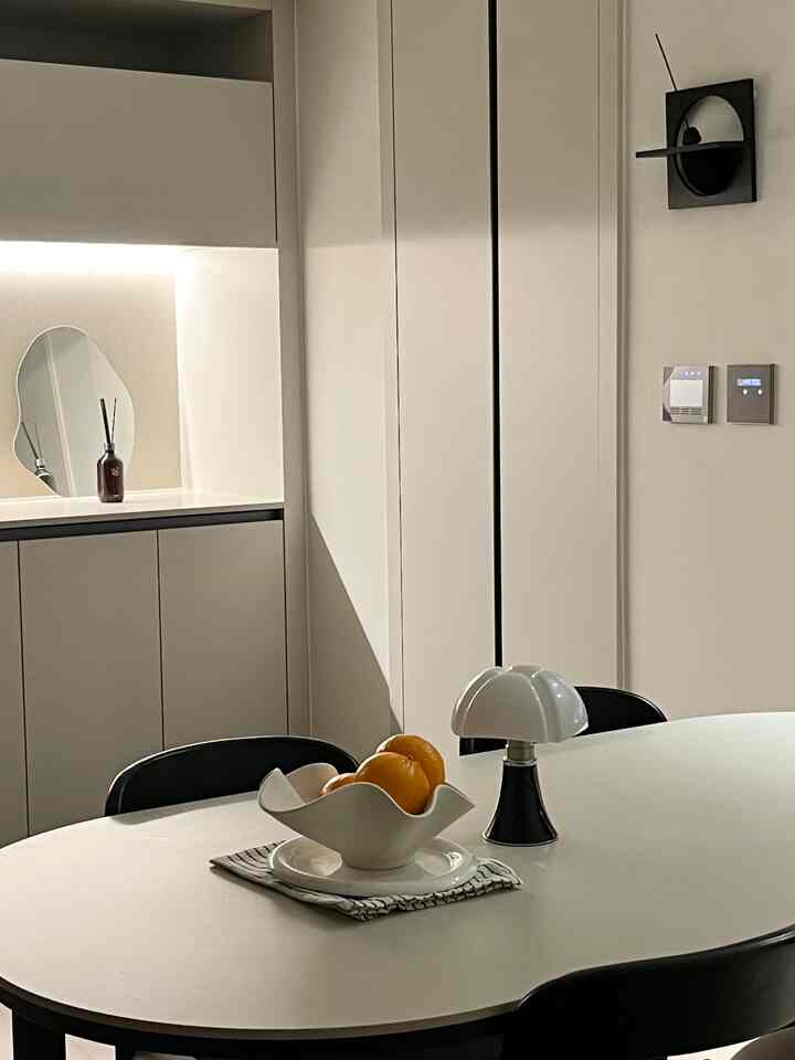 白と黒のトーンのダイニング、楕円形のポーセリンテーブルと黒い椅子が配置されたシンプルでモダンな印象的な空間