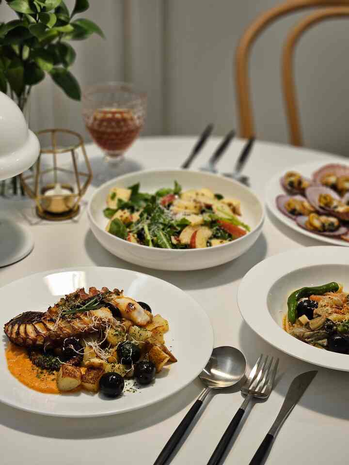 白を基調としたダイニング、丸テーブルに地中海風スペイン料理と白い食器が配された雰囲気のあるモダンなインテリア