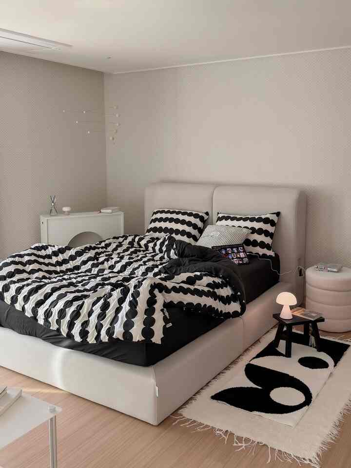 A white and beige toned bedroom featuring an Arco fabric bed frame and black-and-white patterned duvet cover, creating a modern natural atmosphere