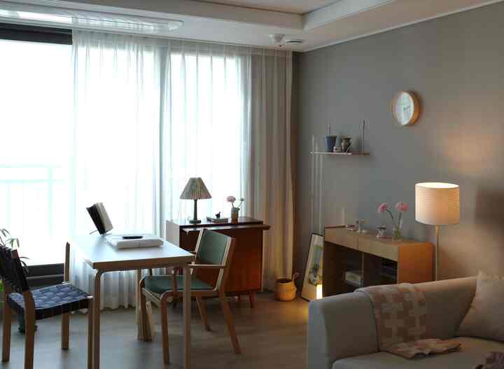 A cozy living room with soft beige and gray tones featuring wood-tone dining table and sofa