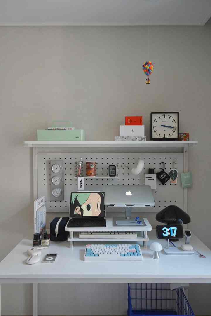 White-toned home office desk featuring a laptop, keyboard, and wall clock in a neat workspace
